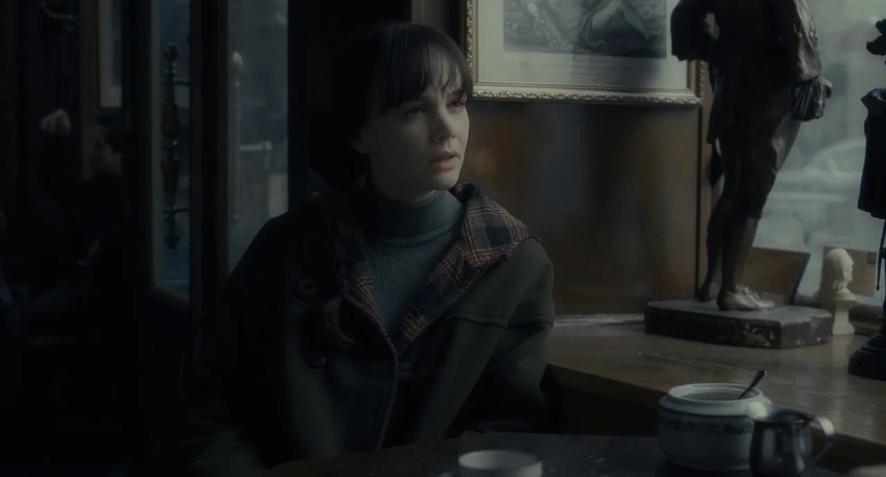 Inside Llewyn Davis (2013) movie still: medium — A dark, wood-paneled establishment features a large window with a view of a street. A woman sits at…