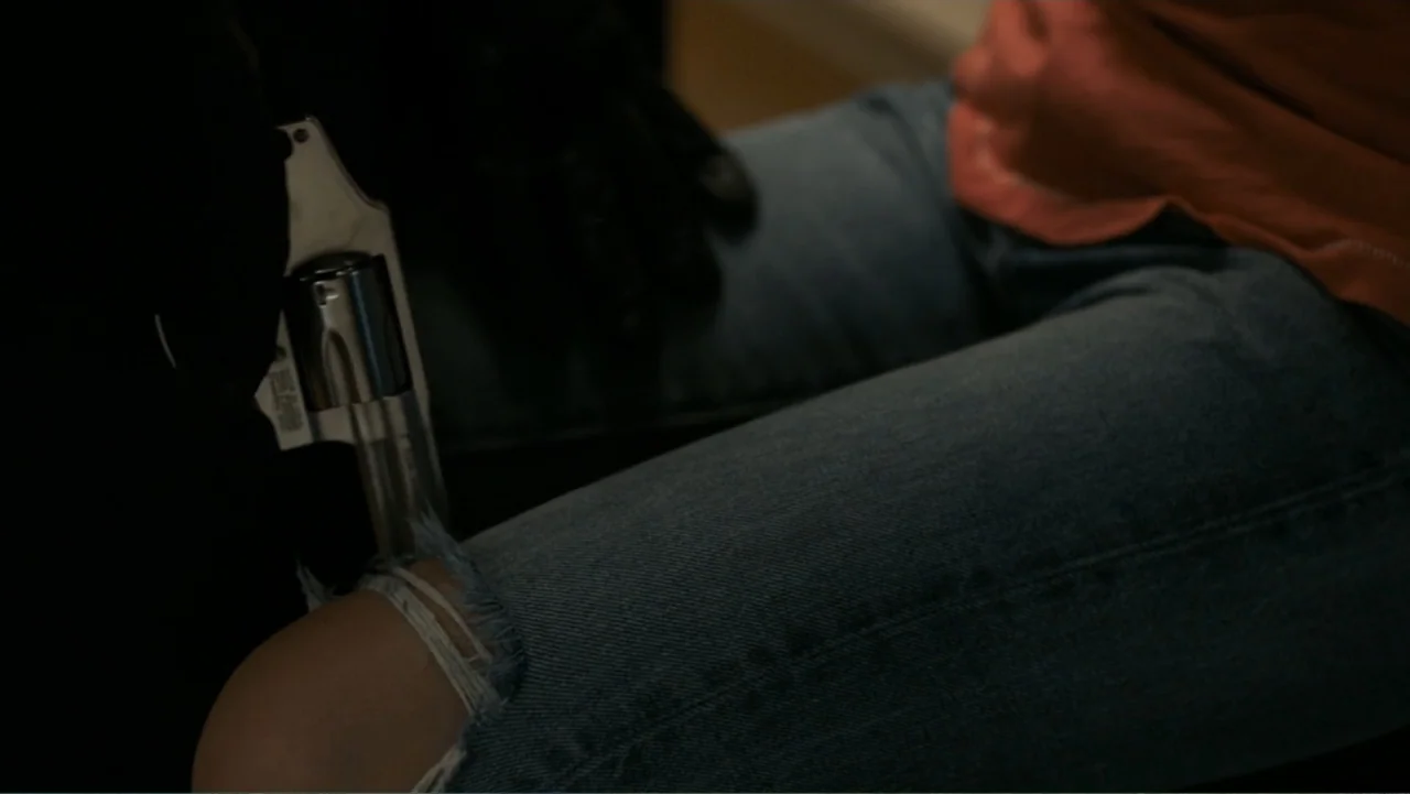 Death Wish (2018) movie still: medium — A dimly lit indoor space features a subject wearing distressed blue jeans and an orange shirt. A dark-gloved…