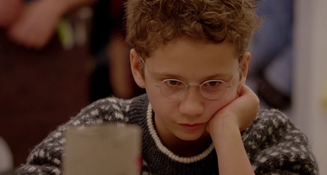 We Are The Best! (2013) movie still: closeup — A young boy sits at a table while wearing a thick patterned wool sweater. He rests his head on his…