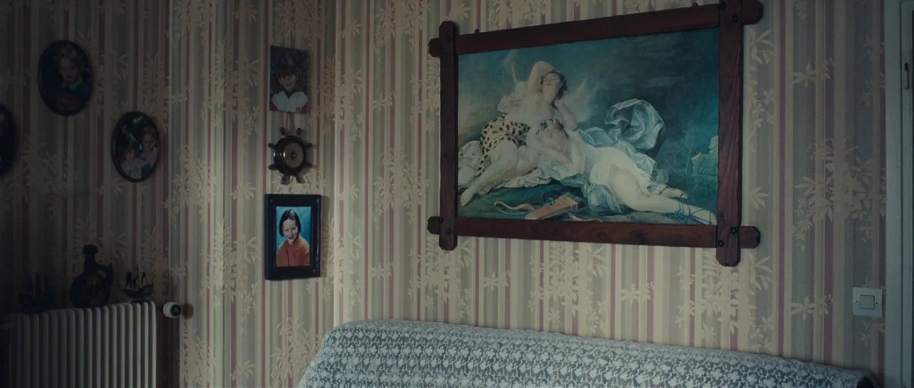 Our Day Will Come (2010) movie still: wide — A domestic space features vertical striped wallpaper and a series of framed personal photographs. A…