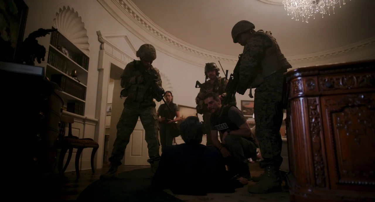 Civil War (2024) movie still: wide — A dimly lit room with curved walls features a large wooden desk and bookshelf. Soldiers stand guard over a man…