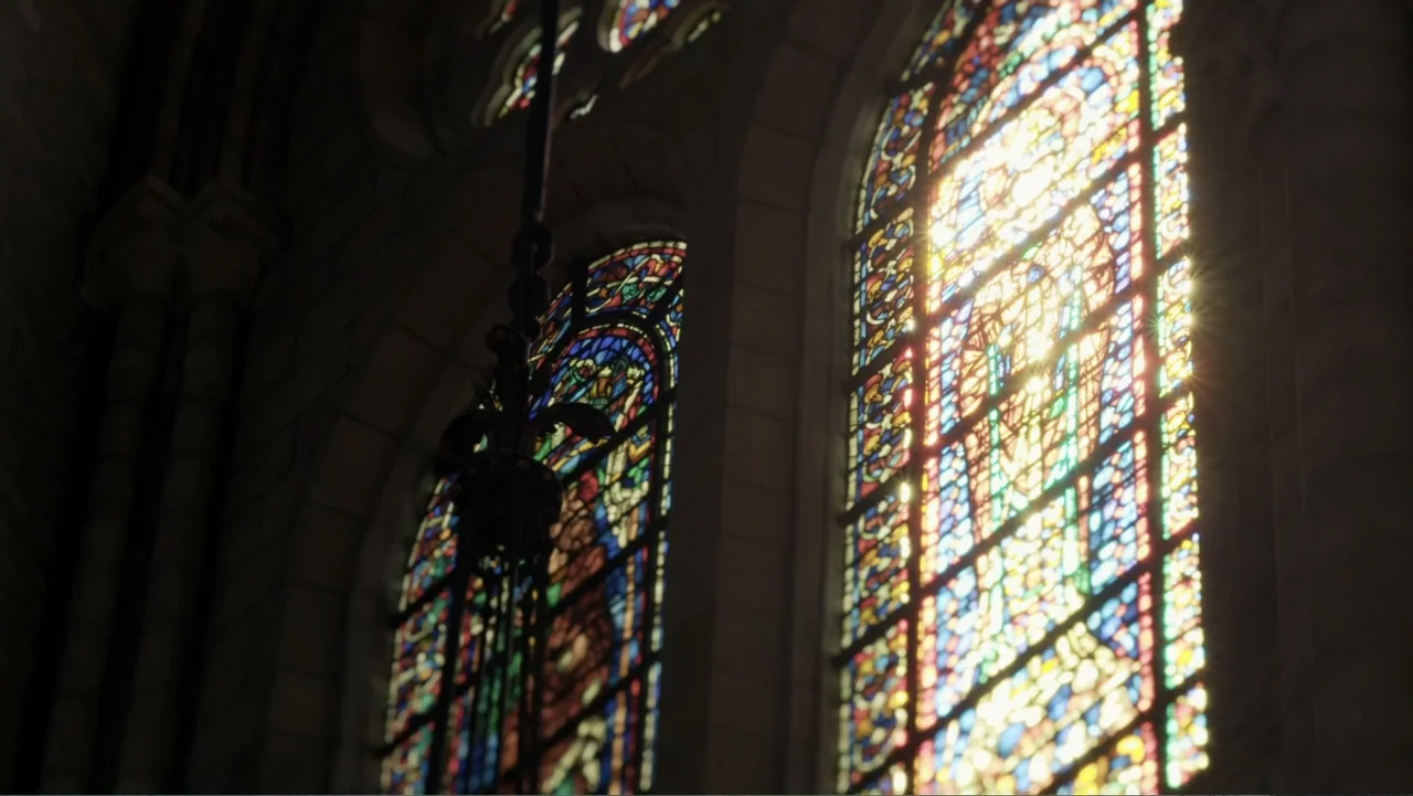 King in the Wilderness (2018) movie still: establishing — Sunlight filters through ornate stained glass windows set into heavy stone cathedral…