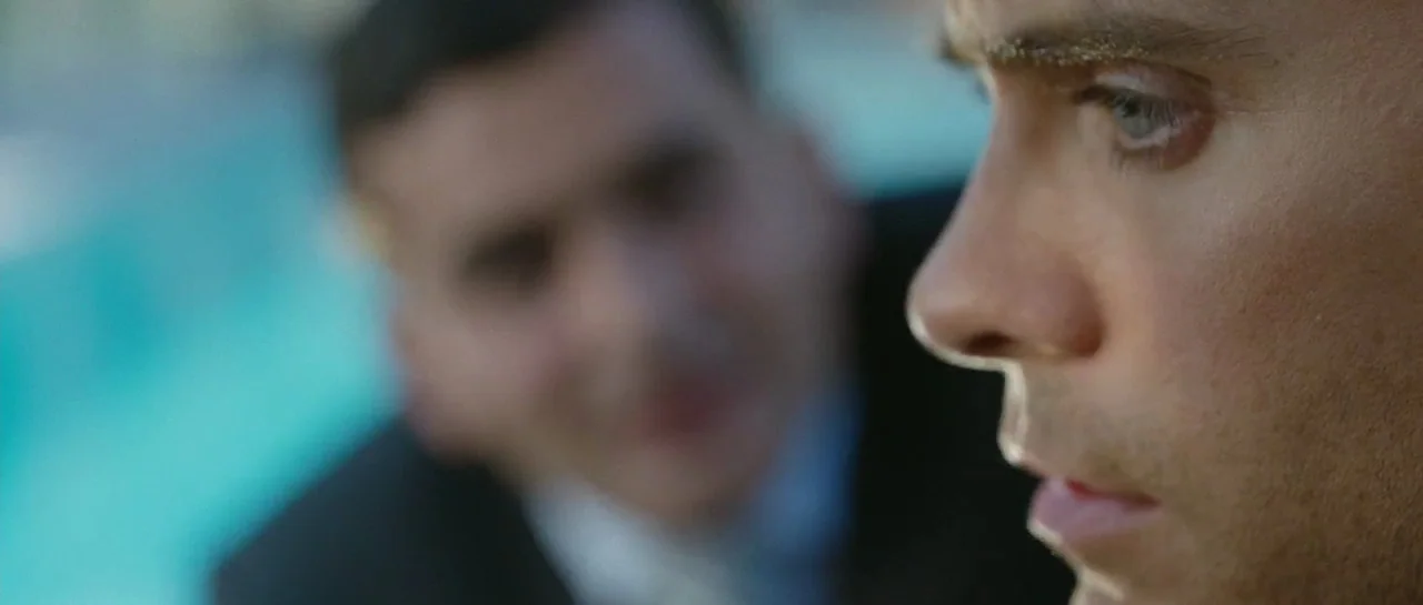 Mr. Nobody (2009) movie still: closeup — A bright outdoor space features a pool edge blurred in the background behind subjects. A man in the…