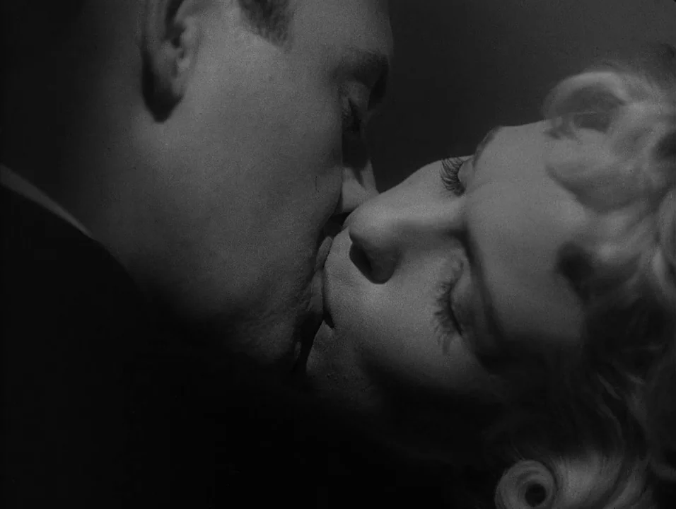 Dreams (1955) movie still: closeup — A dimly lit interior space silhouettes the profiles of a couple. A man and a woman are shown in a close embrace…