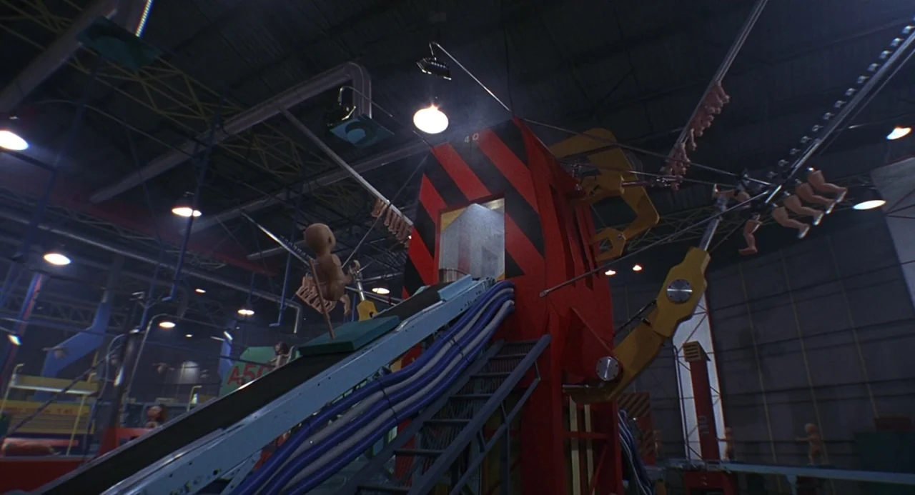 Child’s Play 2 (1990) movie still: wide — A sprawling industrial toy factory floor features elevated conveyor belts and red machinery components.…