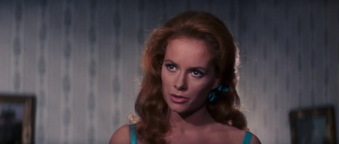 Thunderball (1965) movie still: closeup — A woman stands in a room with vertical striped wallpaper. She is positioned against a neutral background…