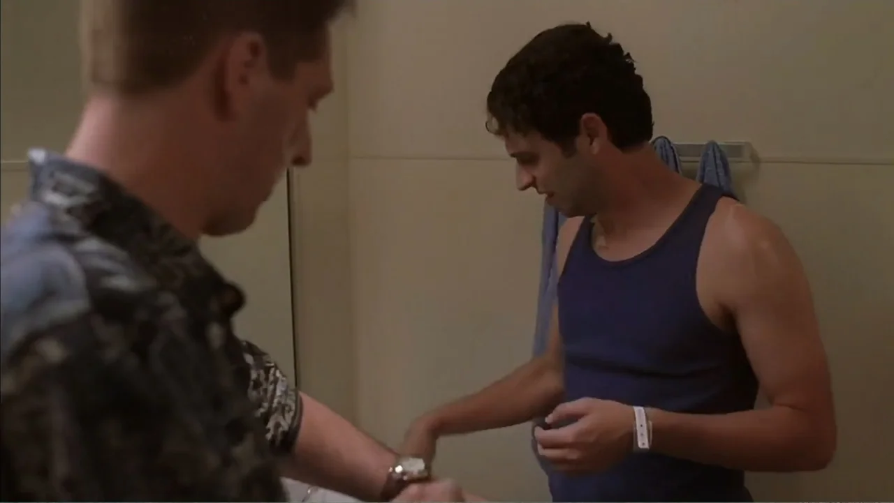 Day of the Dead 2: Contagium (2005) movie still: medium — A small, plain bathroom with beige walls features two men interacting near a sink. One man…