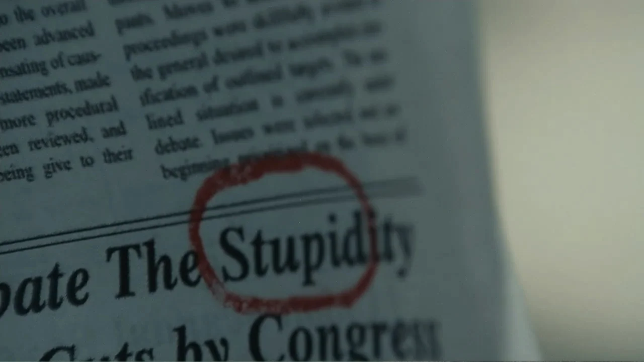 Mr. Brooks (2007) movie still: closeup — A close-up view shows a section of a newspaper printed with black text. A hand-drawn red circle highlights…