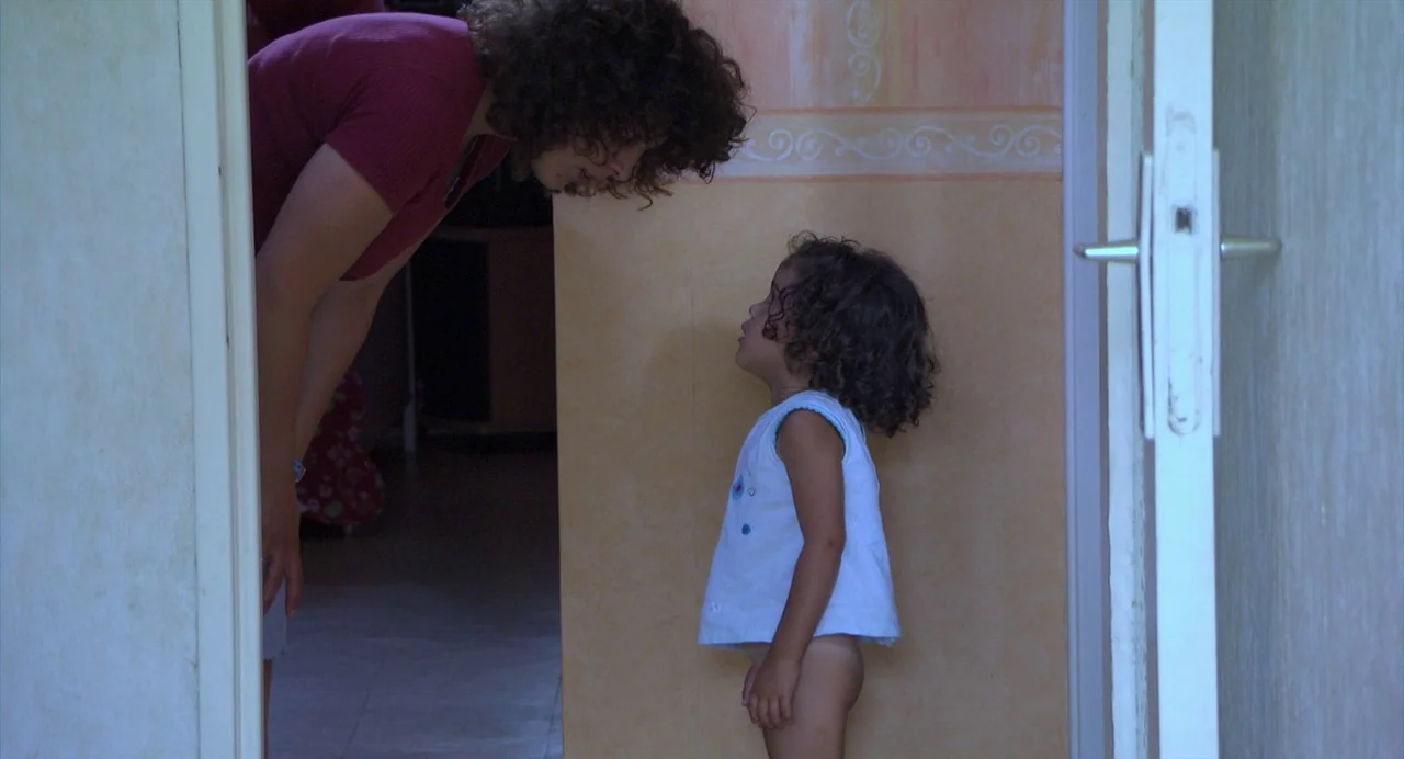 The Secret of the Grain (2007) movie still: medium — A domestic hallway with peach-colored walls featuring painted trim patterns near the ceiling. A…