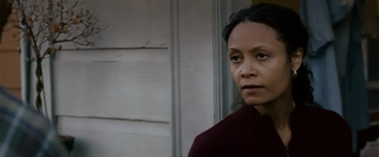 The Pursuit of Happyness (2006) movie still: medium — A woman stands on a porch with white siding and a blue jacket hanging behind. The woman looks…
