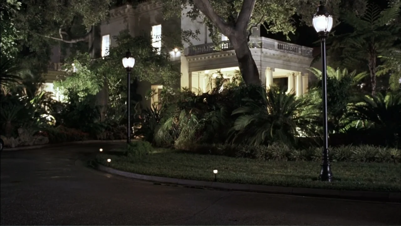 A Cinderella Story (2004) movie still: establishing — A dark, paved driveway curves toward the entrance of a large classical style mansion. Lush…