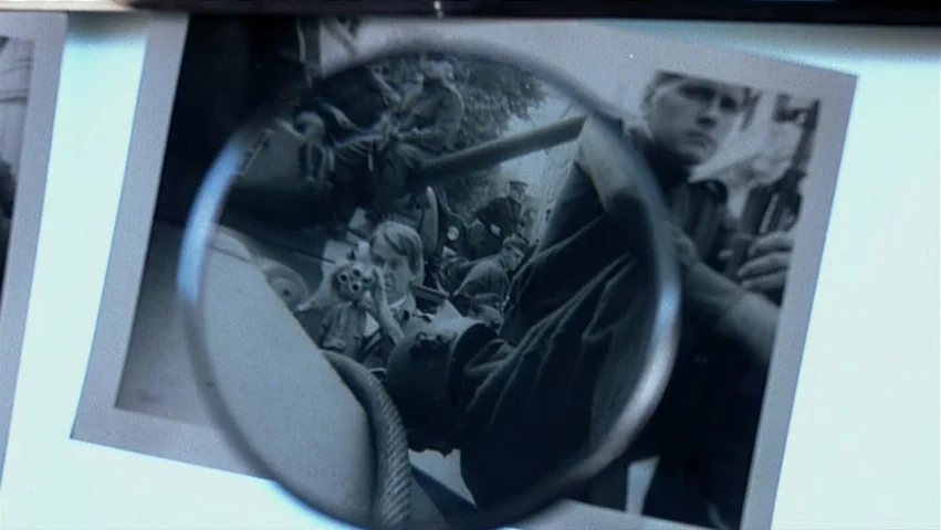 The Unbearable Lightness of Being (1988) movie still: closeup — A close-up view of a black-and-white photograph being examined with a round…