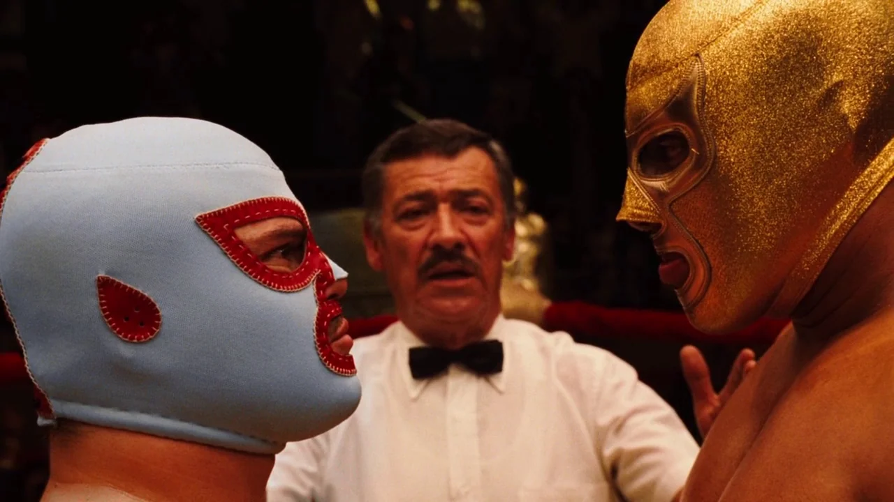 Nacho Libre (2006) movie still: medium — A boxing ring with a referee standing between two wrestlers in masks. The wrestlers face each other while…