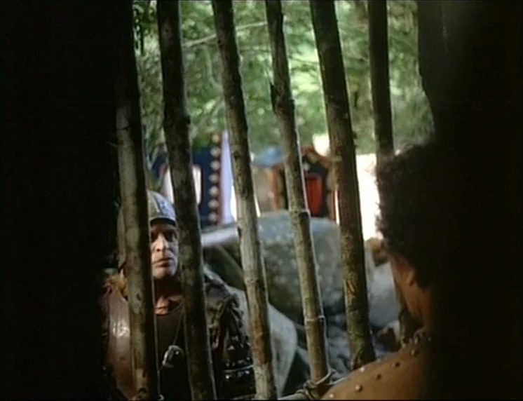 Aguirre, The Wrath Of God (Aguirre, der Zorn Gottes) (1972) movie still: medium — A wooden barred cage stands in a natural outdoor clearing. A man…