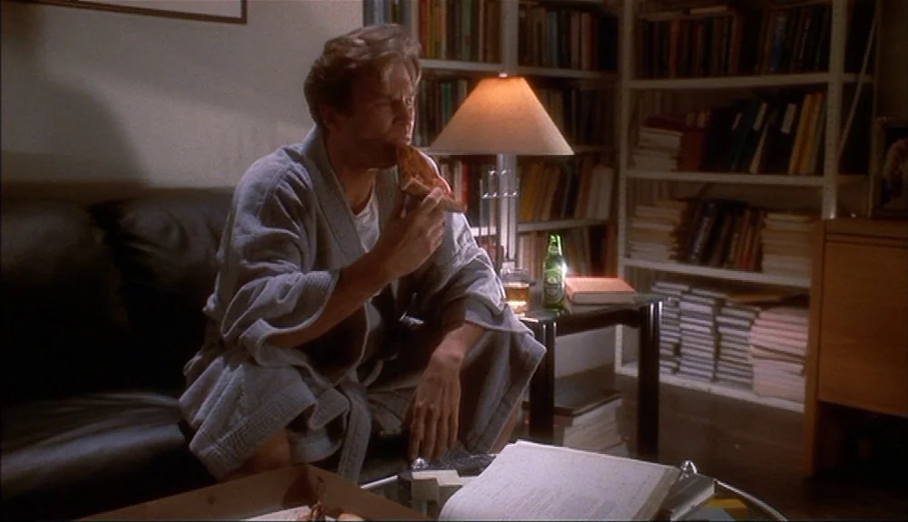 The Mirror Has Two Faces (1996) movie still: medium — A dimly lit room contains a leather couch and shelves packed with numerous books. A man…
