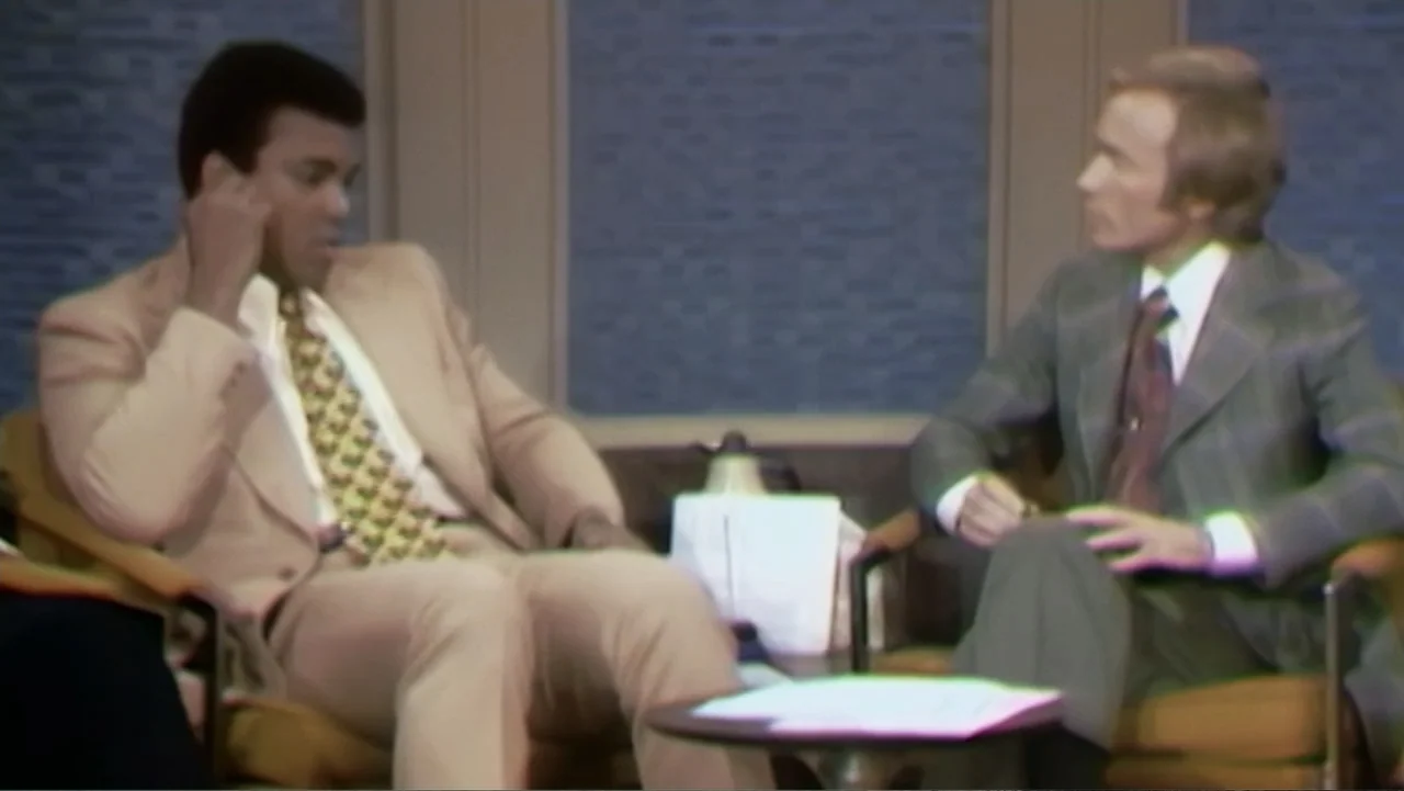 Ali & Cavett: The Tale of the Tapes (2018) movie still: medium — A television interview set features two upholstered chairs with a small table…