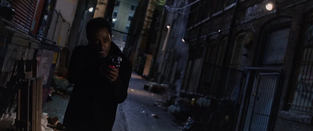 Death Note (2017) movie still: medium — A narrow city passage at night features brick walls and accumulated trash. A man in dark clothing walks…