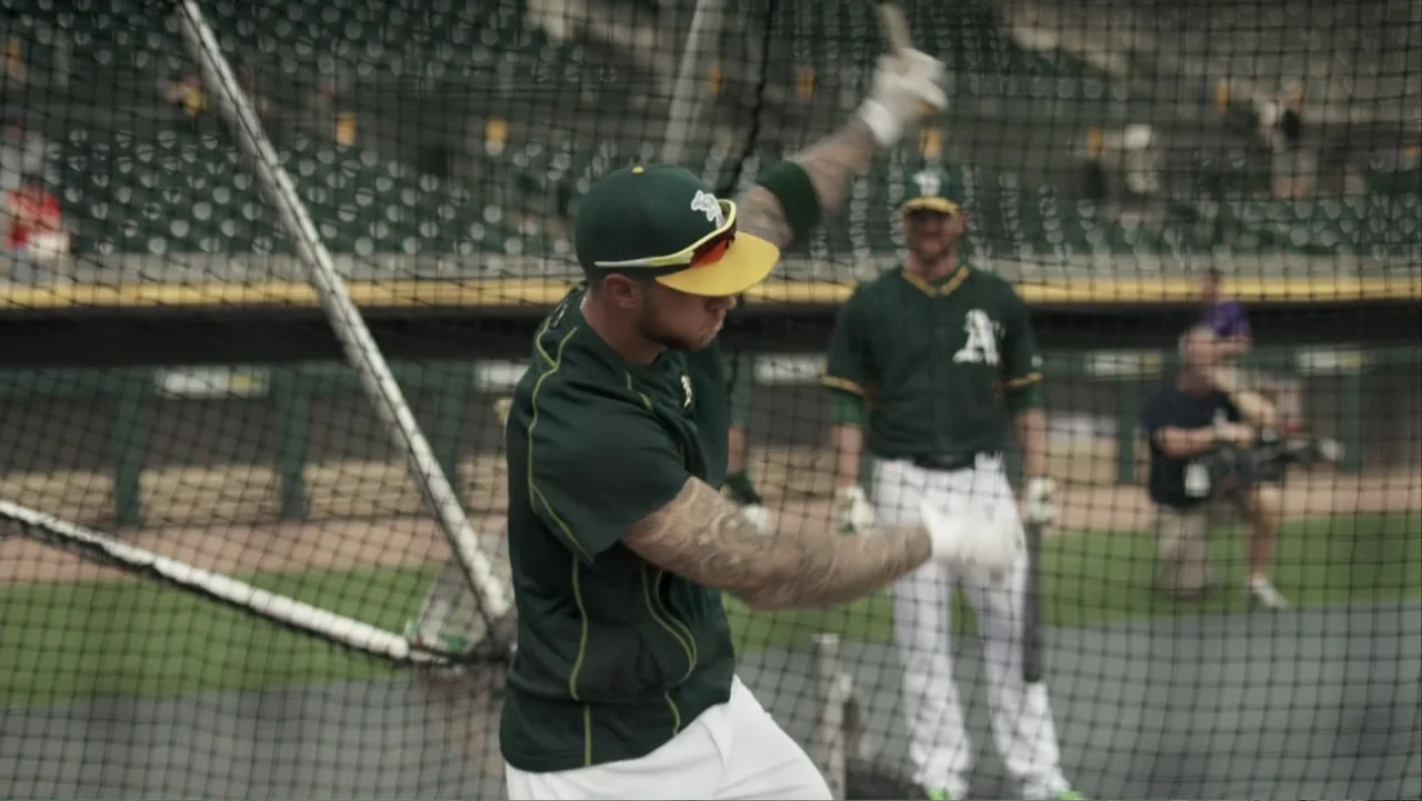 Ferrell Takes the Field (2015) movie still: medium — A professional baseball batting cage with a large safety net surrounding the training area. An…