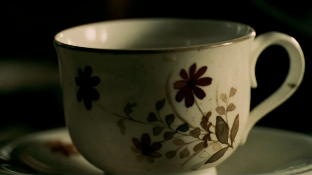 The Texas Chainsaw Massacre: The Beginning (2006) movie still: closeup — A close-up of a porcelain teacup with delicate brown floral patterns on…