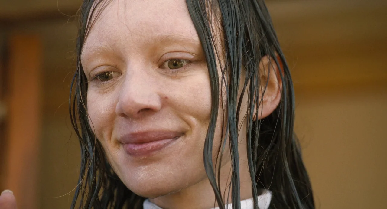The First Omen (2024) movie still: closeup — A close-up shot focuses on a person with wet hair in an outdoor setting. The woman looks down while…