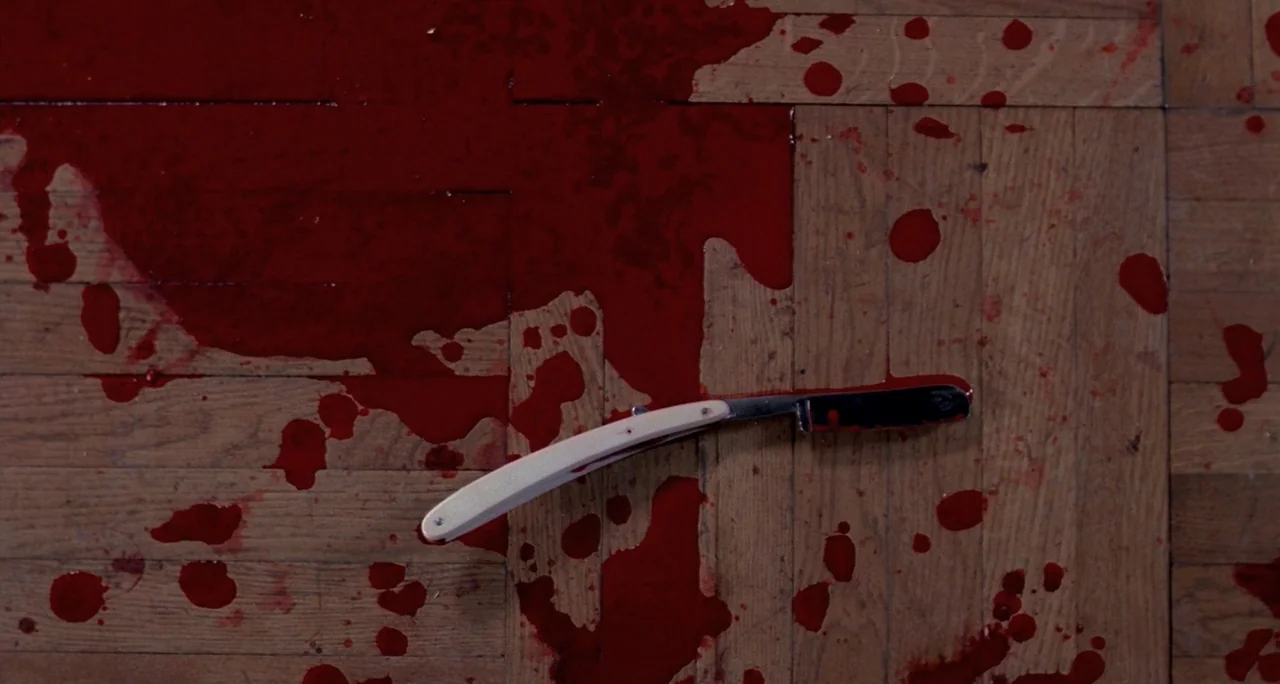 Tenebre (1982) movie still: closeup — A polished wooden parquet floor is covered in pools and splatters of bright red blood. A single vintage…