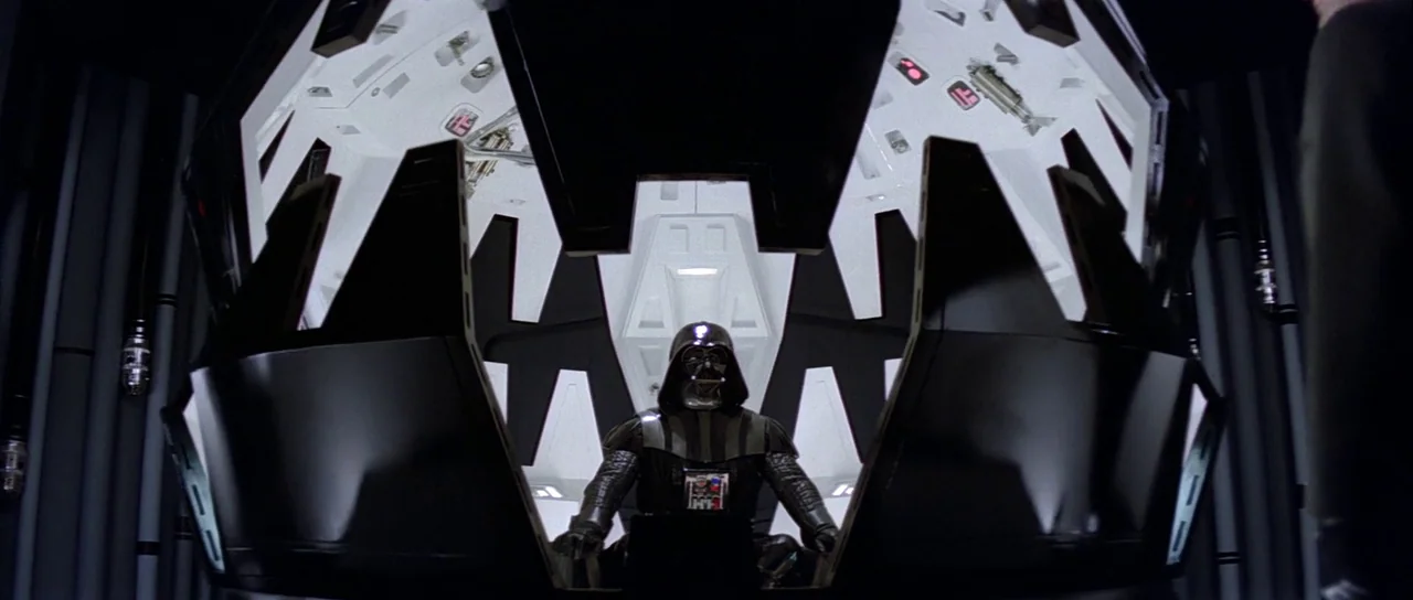 The Empire Strikes Back (1980) movie still: medium — A dark, circular mechanical chamber with white interior panels and geometric lighting fixtures.…