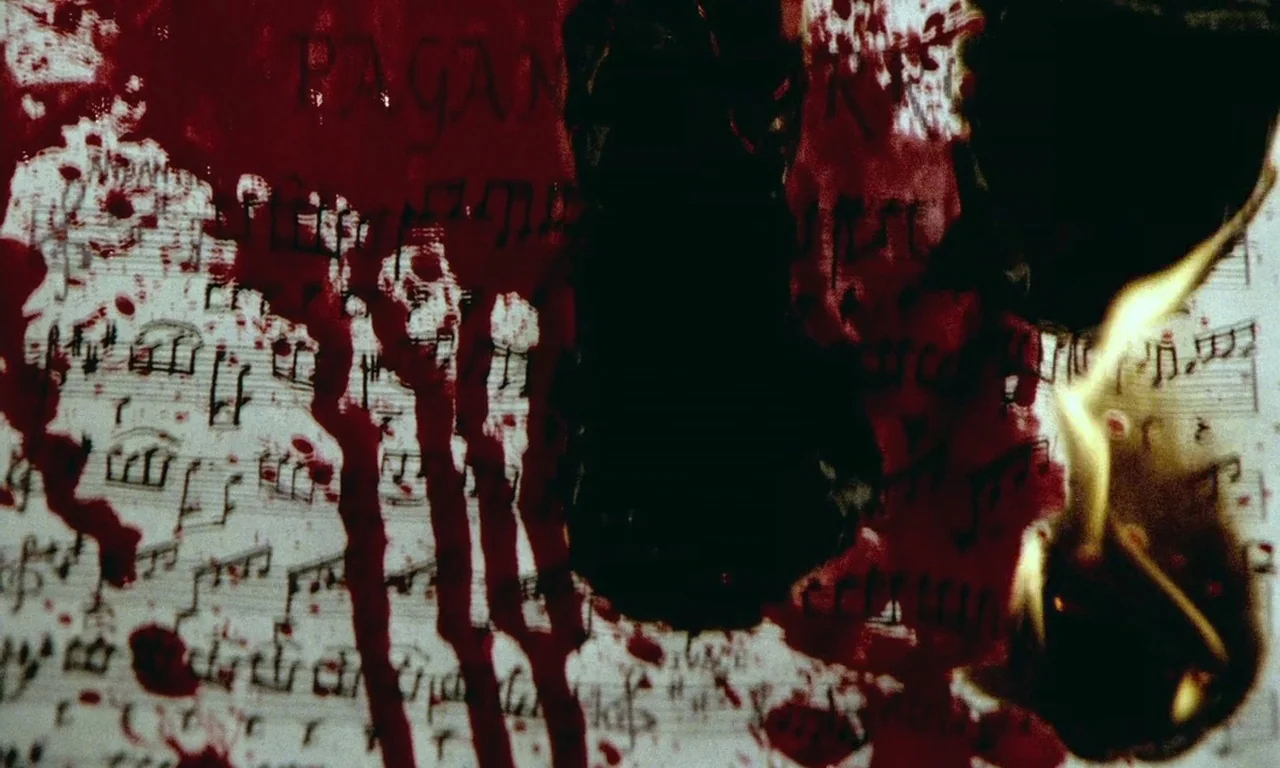 Paganini Horror (1989) movie still: closeup — A sheet of musical notation is covered in streaks of bright red blood. A central section of the paper…