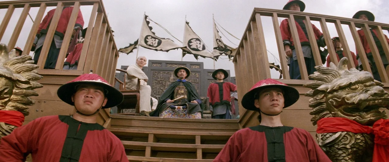 Once Upon a Time in China (1991) movie still: wide — A wooden platform features a central dignitary surrounded by guards in red tunics. Several…