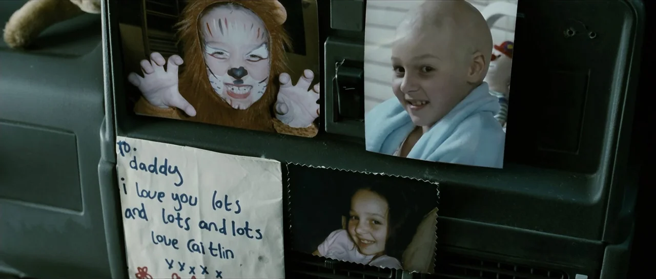 The Oxford Murders (2008) movie still: closeup — A collection of candid photographs and a handwritten letter are taped to a dark dashboard. The…