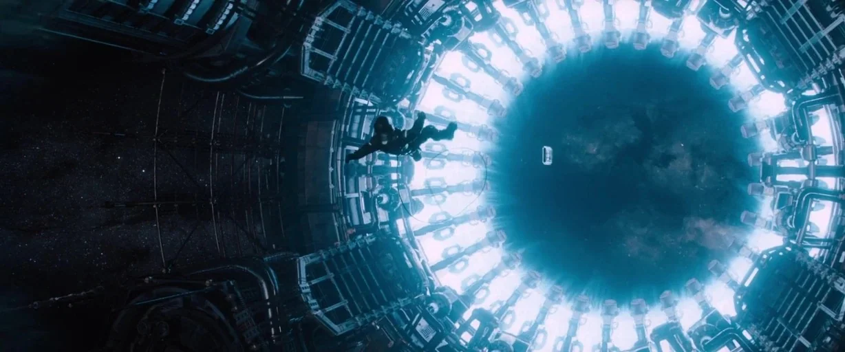 Passengers (2016) movie still: wide — A complex circular mechanical structure glows with intense white light against deep space. An astronaut in a…