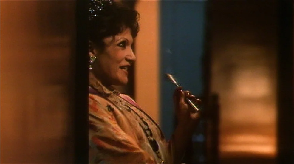 Union City (1980) movie still: medium — A dark, blurred hallway provides a framed view of an individual standing near a doorway. The person holds a…