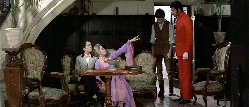 Whity (1971) movie still: wide — A furnished interior with dark wood paneling, ornate chairs, and arched ceiling alcoves. A group of people interact…