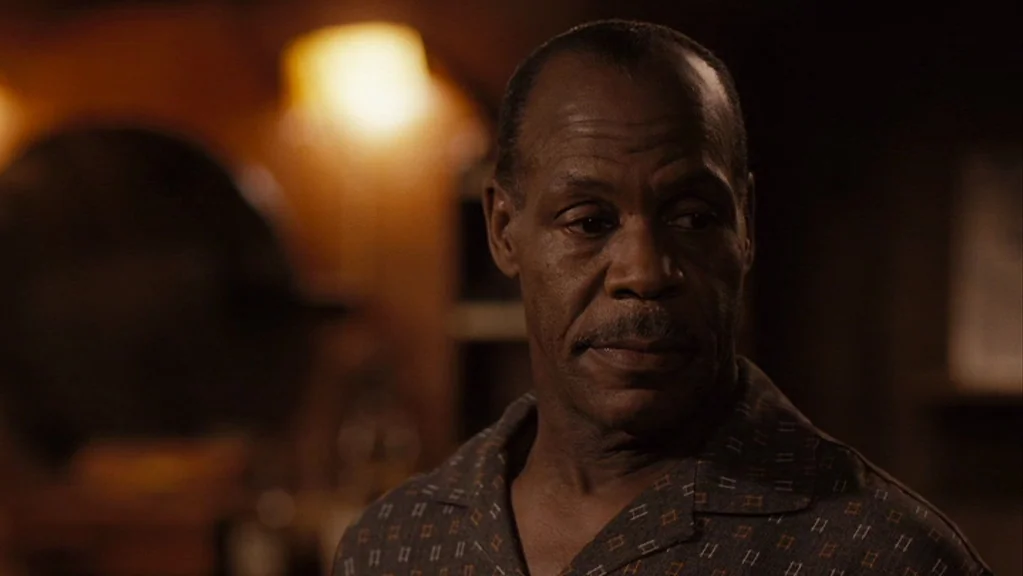 Honeydripper (2007) movie still: closeup — A dimly lit interior space with soft background warmth from a lamp. An elderly man with a thin mustache…