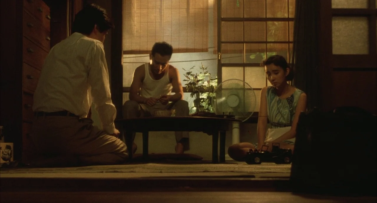 The Discarnates (1988) movie still: medium — A Japanese tatami room features shoji screen partitions and a low central wooden table. Three people…