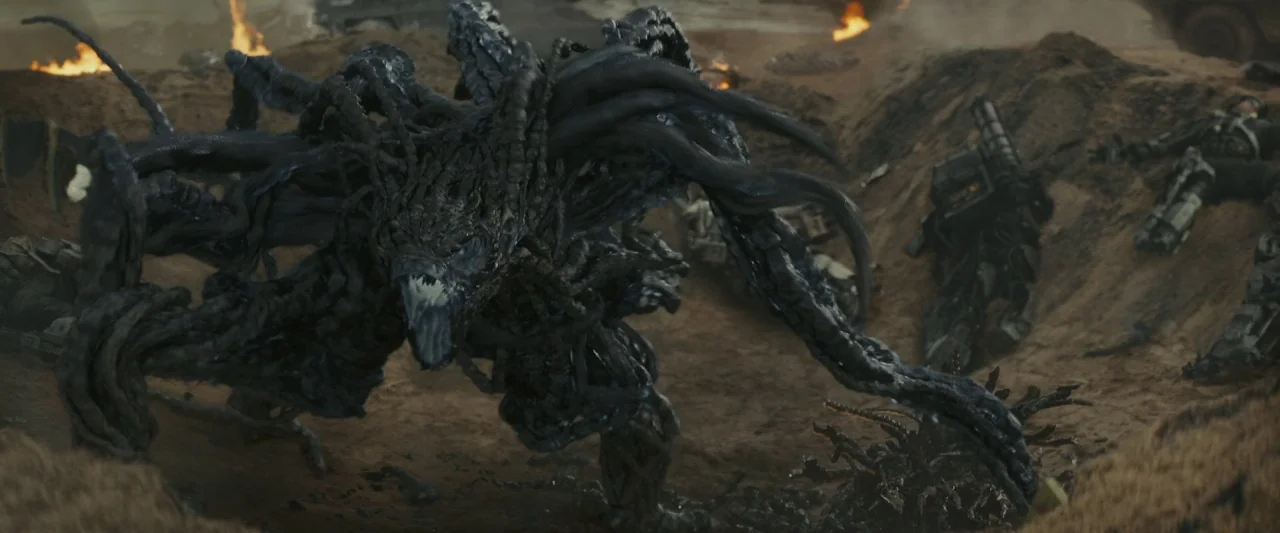 Edge of Tomorrow (2014) movie still: fullbody — A war-torn brown dirt landscape features fire and remnants of fallen armored soldiers. A massive…