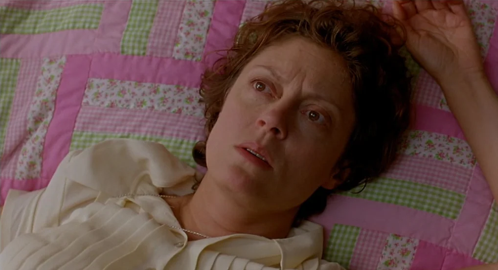 Dead Man Walking (1995) movie still: closeup — A woman lies on a pink, white, and green gingham floral quilted fabric surface. She is positioned on…