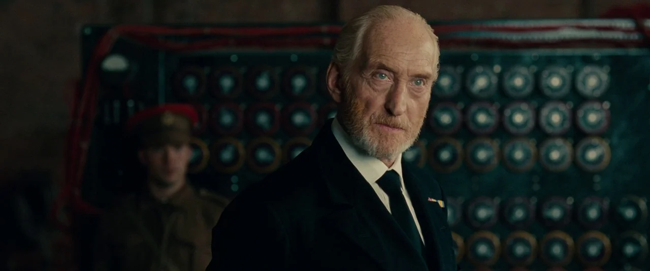 The Imitation Game (2014) movie still: medium — An interior space features a dark electronic control panel with numerous circular knobs. An older…