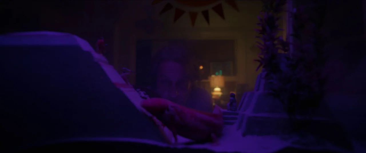 Bardo: False Chronicle of a Handful of Truths (2022) movie still: medium — A dimly lit room interior featuring a man looking over a small diorama…