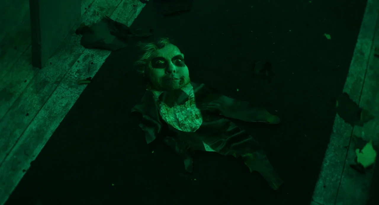Beetlejuice Beetlejuice (2024) movie still: closeup — A darkened interior floor surface is covered in bits of debris. A head and upper torso of a…