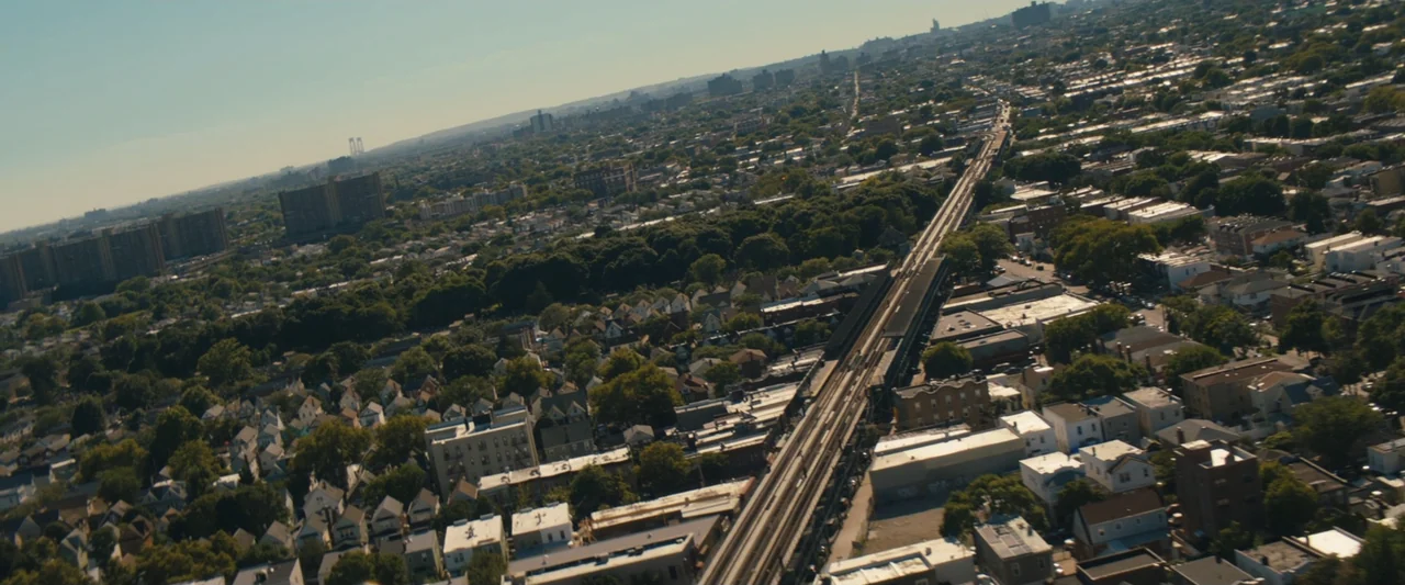 The Sun Is Also a Star (2019) movie still: establishing — An aerial view of a dense residential neighborhood featuring a long elevated train track.…