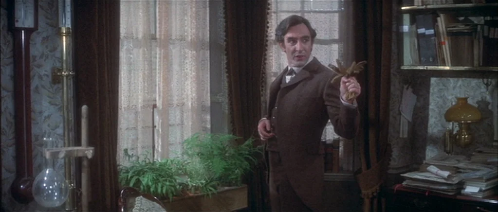 The Private Life of Sherlock Holmes movie still: medium — A cluttered Victorian-era room contains a wall barometer, a desk, and a window. A man in a…