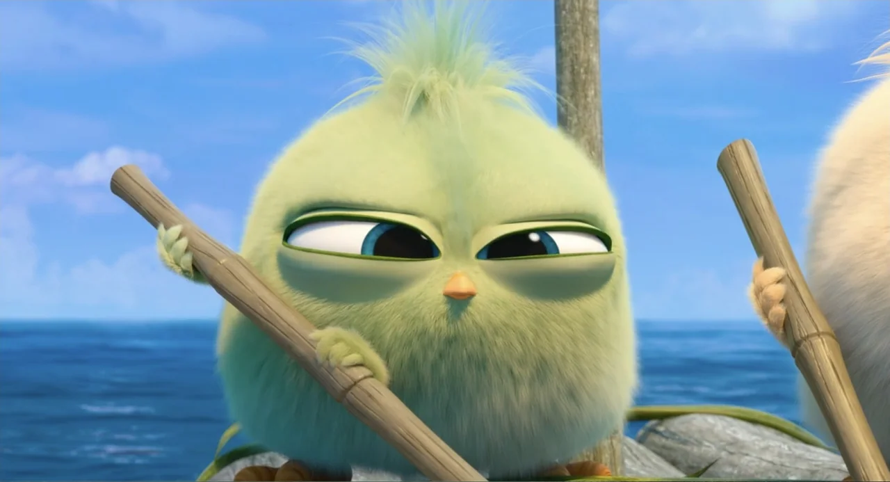 The Angry Birds Movie 2 (2019) movie still: closeup — A small, round green creature sits on a wooden raft in the middle of water. The character…