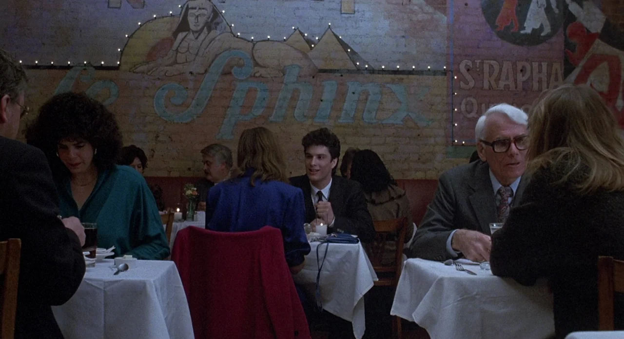 Brain Damage (1988) movie still: medium — A restaurant dining room features a brick wall painted with a sphinx mural. Several patrons sit at small…