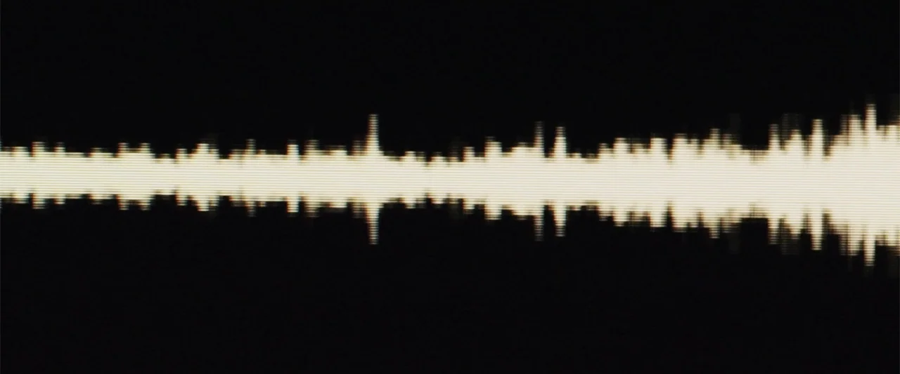 Anna (2013) movie still: establishing — An abstract visual representation of an audio signal on a black display. A bright cream-colored waveform…