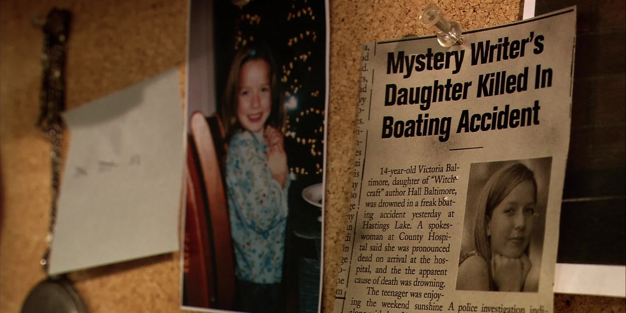 Twixt (2011) movie still: closeup — A cork bulletin board contains a photograph of a smiling child and a news clipping. The printed newspaper…