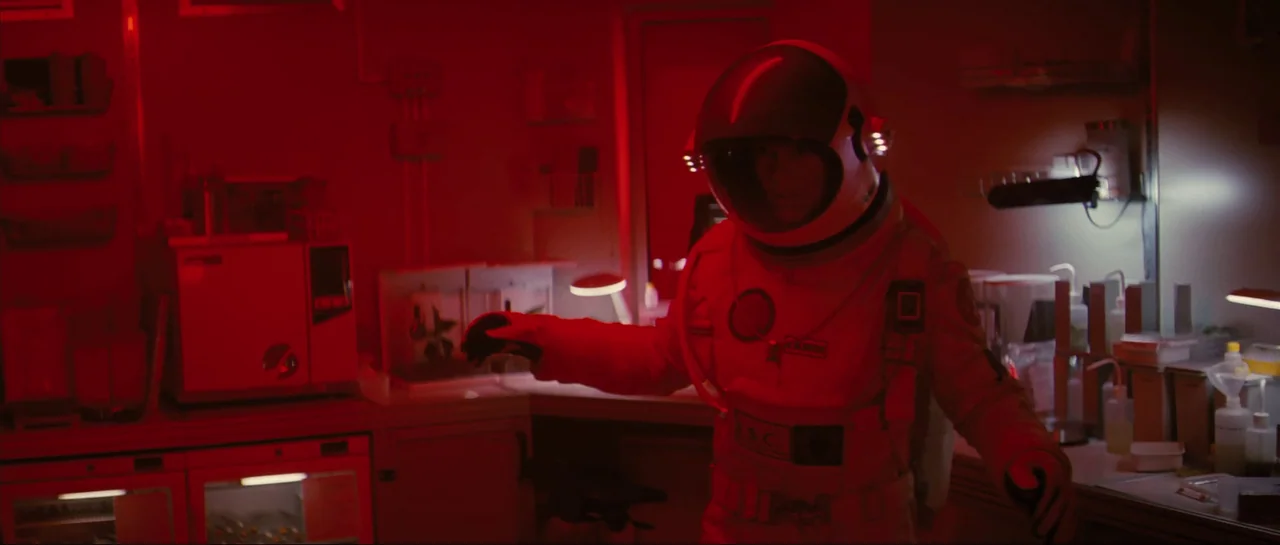 The Last Days On Mars (2013) movie still: medium — A sterile research facility is flooded with deep red emergency lighting. An astronaut in a…