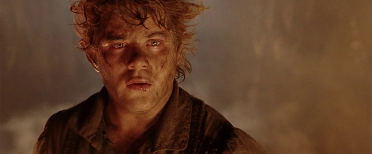 The Lord of The Rings: The Return of the King (2003) movie still: closeup — A soot-covered man stands in a dark, warm-lit environment filled with…