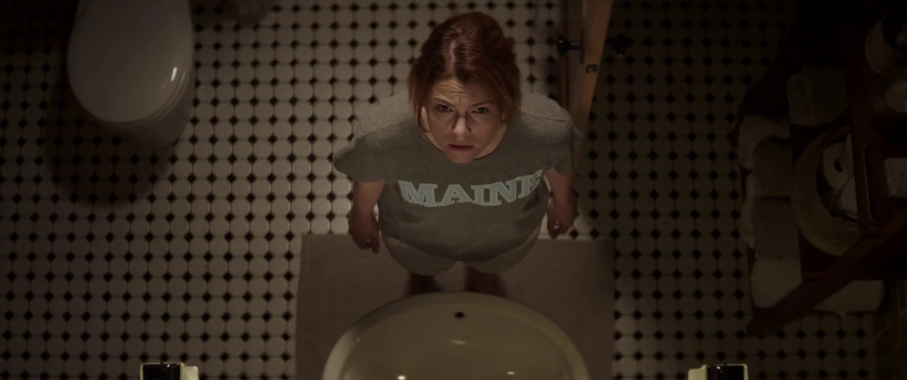Pet Sematary (2019) movie still: medium — A small room features black-and-white hexagonal floor tiles and a white ceramic sink basin. A woman stands…