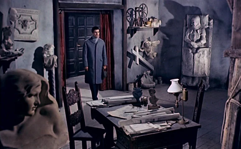 Mill of the Stone Women (1960) movie still: wide — An cluttered studio space contains multiple classical sculptures and architectural blueprints on…