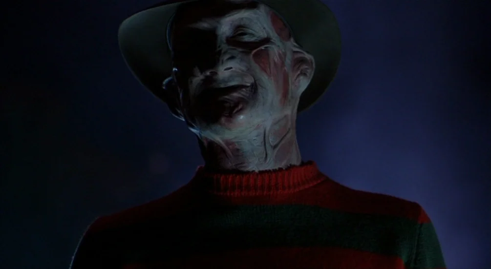 Freddy’s Dead: The Final Nightmare (1991) movie still: closeup — A dark, ambiguous environment with no visible architectural details. A scarred man…